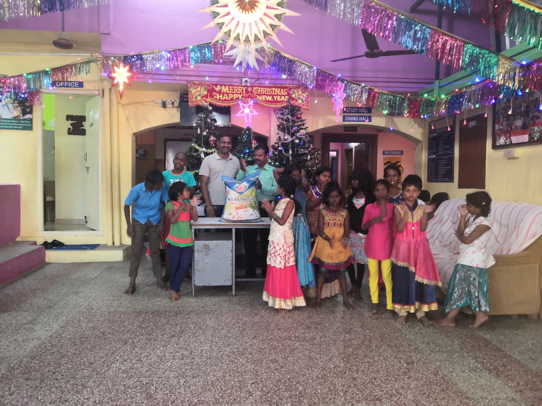 Handing over a sack of rice to the orphanage staff while children gather around