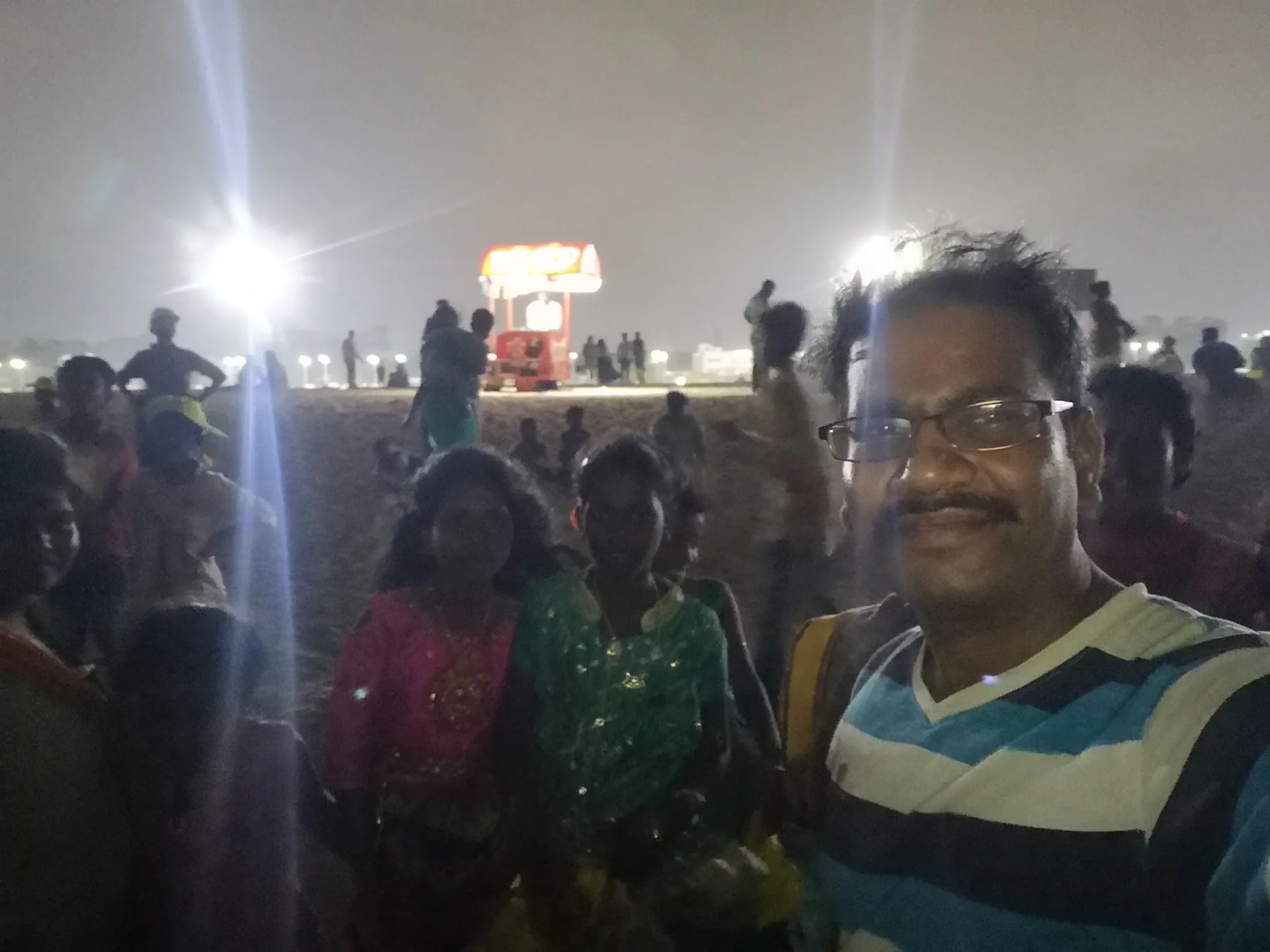 Selfie with children at Marina Beach near a lit food stall in the evening