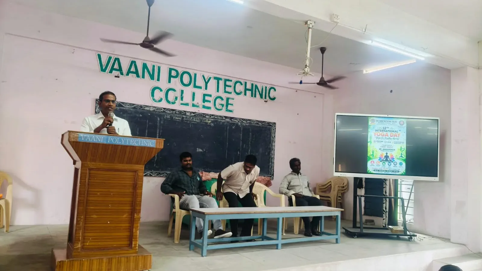 Stage view with podium and Yoga Day display at Vaani Polytechnic College
